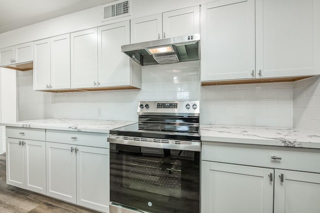 kitchen with white cabinets, electric stove, light stone countertops, light wood-type flooring, and tasteful backsplash