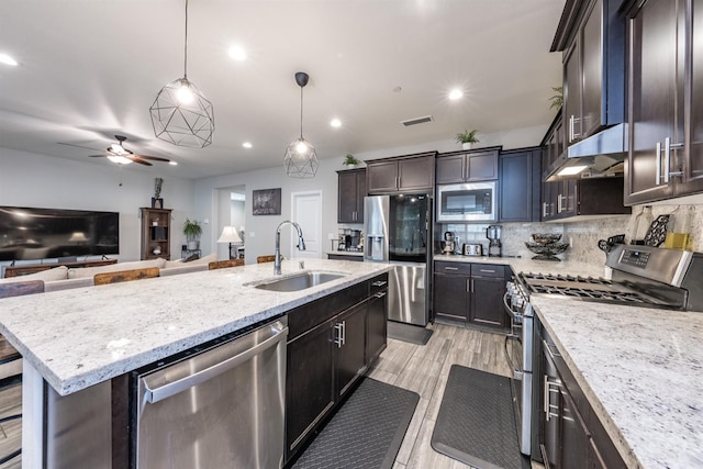 kitchen featuring pendant lighting, a kitchen island with sink, sink, tasteful backsplash, and stainless steel appliances