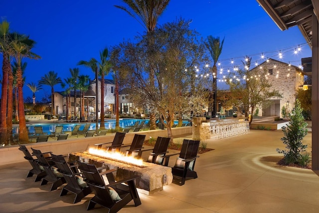 view of property's community featuring a swimming pool, a patio, and a fire pit