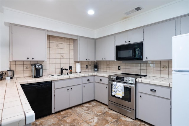 kitchen with black appliances, tile counters, sink, and tasteful backsplash