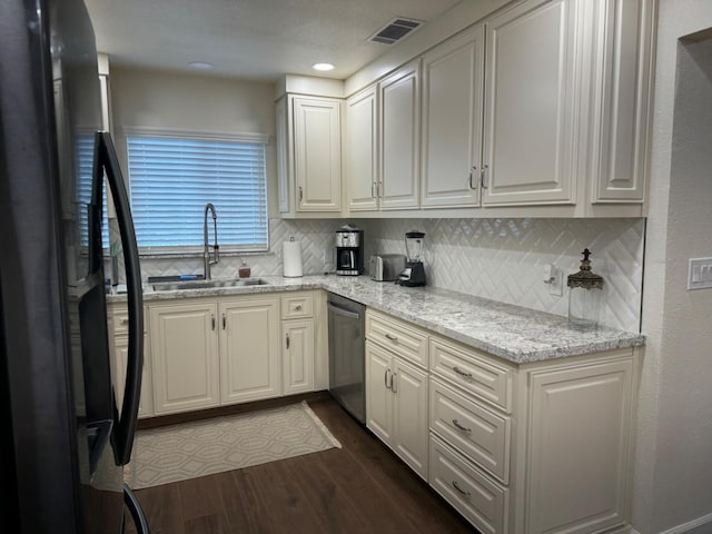 kitchen featuring sink, dark wood-type flooring, light stone counters, stainless steel dishwasher, and fridge