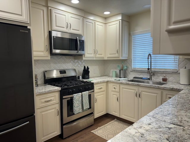 kitchen with light stone countertops, decorative backsplash, dark hardwood / wood-style flooring, stainless steel appliances, and sink