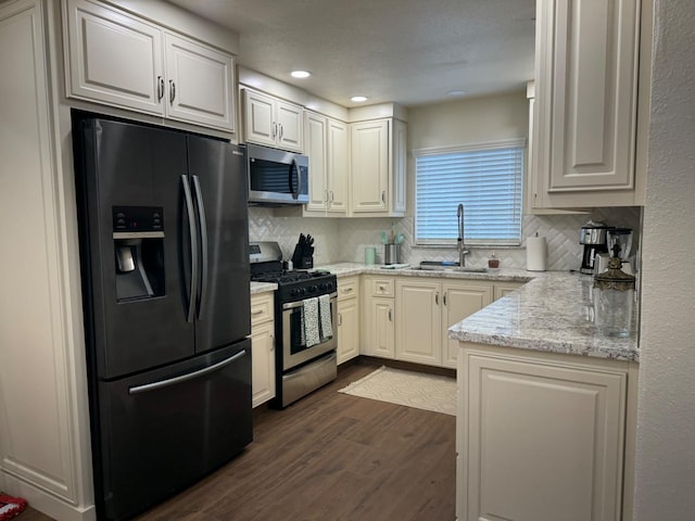 kitchen featuring sink, dark hardwood / wood-style floors, tasteful backsplash, white cabinetry, and stainless steel appliances