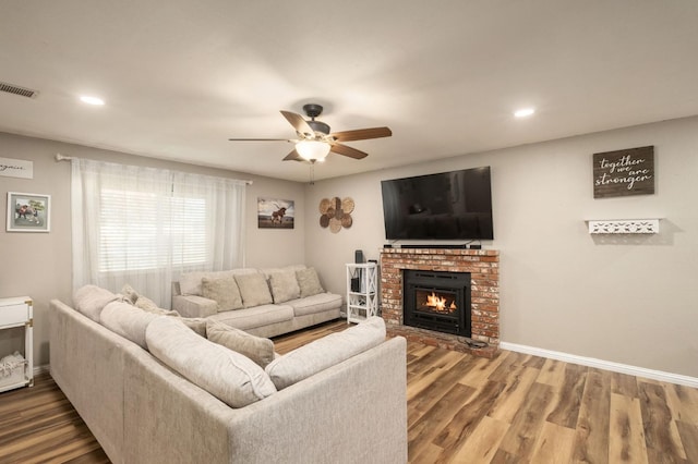 living room featuring ceiling fan, wood-type flooring, and a fireplace