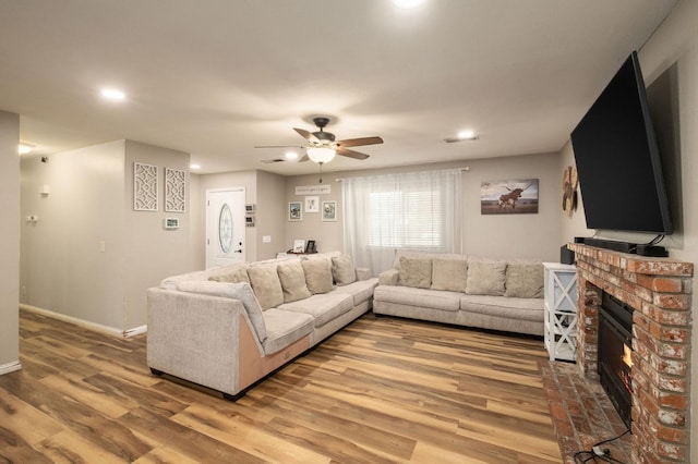 living room featuring a brick fireplace, hardwood / wood-style flooring, and ceiling fan