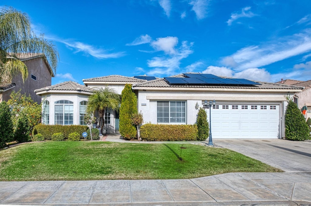 view of front of property featuring solar panels, a garage, and a front lawn