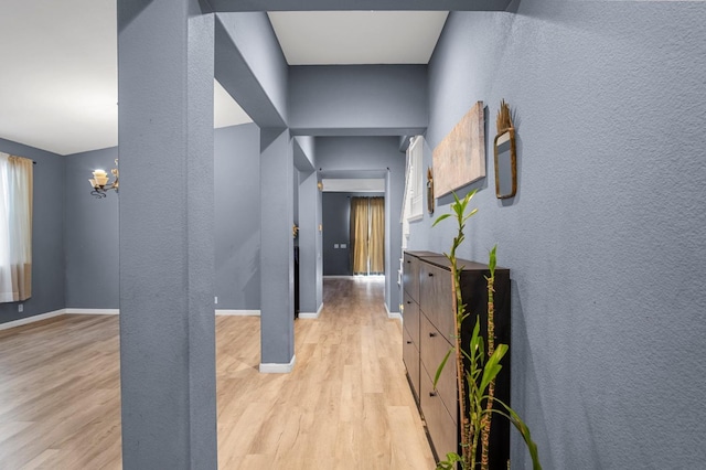 corridor featuring light hardwood / wood-style flooring and a chandelier