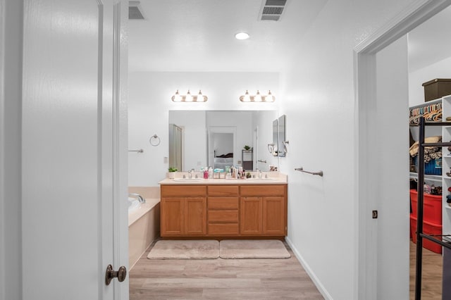 bathroom with a tub, hardwood / wood-style floors, and vanity