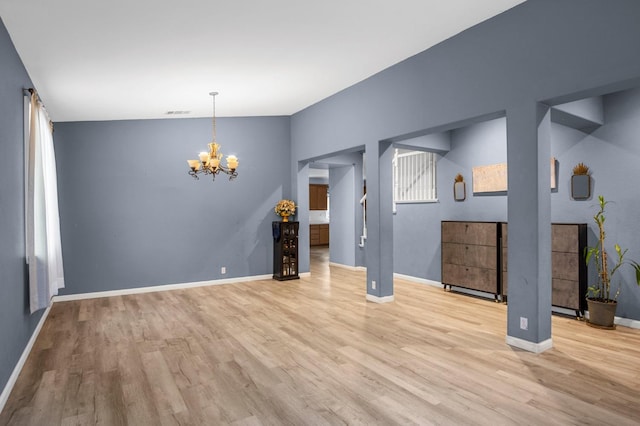 unfurnished room with light wood-type flooring and a notable chandelier