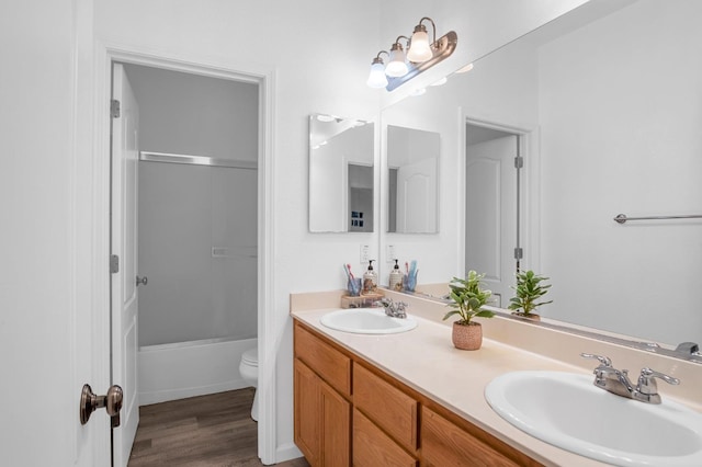 full bathroom with hardwood / wood-style flooring, vanity, shower / bathtub combination, and toilet