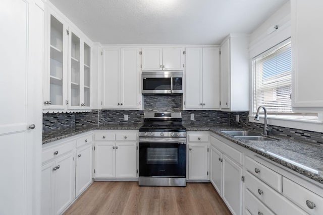 kitchen featuring sink, stainless steel appliances, light stone counters, light hardwood / wood-style flooring, and white cabinets