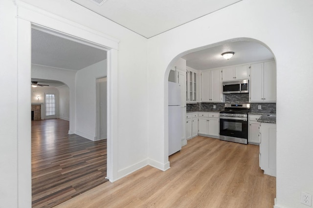 kitchen featuring light hardwood / wood-style flooring, ceiling fan, tasteful backsplash, white cabinetry, and stainless steel appliances