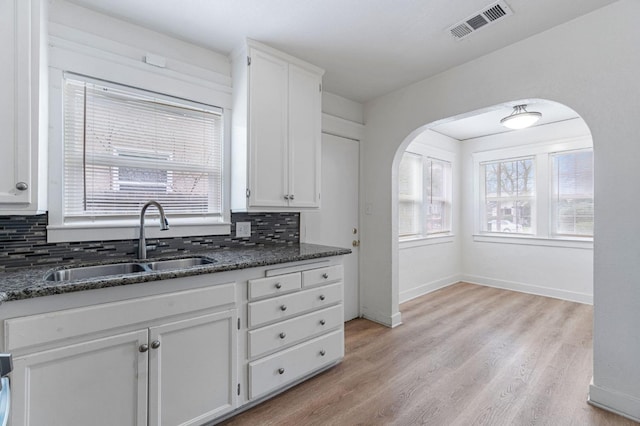 kitchen with tasteful backsplash, sink, white cabinets, and dark stone counters