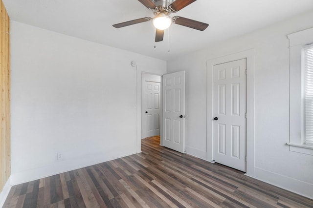 unfurnished bedroom with ceiling fan and dark wood-type flooring