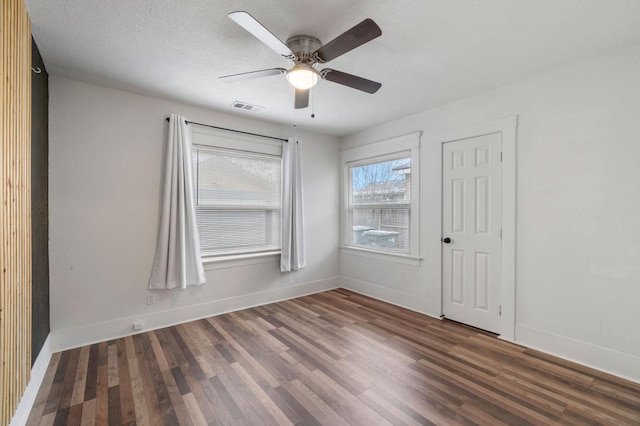 empty room with a textured ceiling, ceiling fan, and dark wood-type flooring