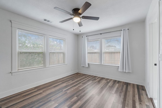 unfurnished room featuring plenty of natural light, dark wood-type flooring, and ceiling fan