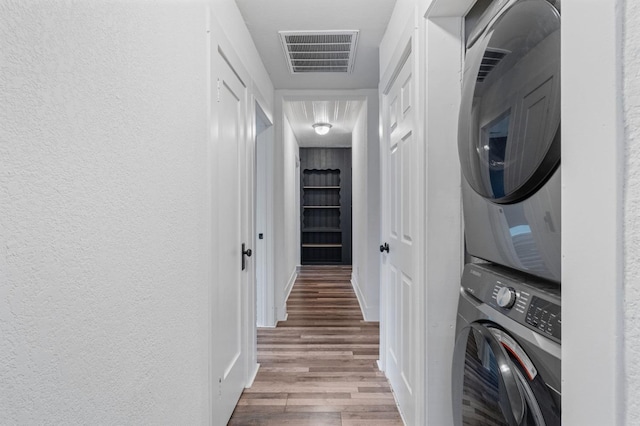 clothes washing area with wood-type flooring and stacked washing maching and dryer