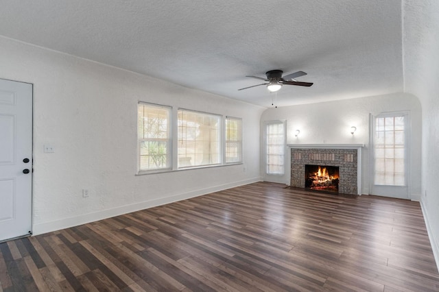 unfurnished living room with a fireplace, a textured ceiling, dark hardwood / wood-style flooring, and ceiling fan