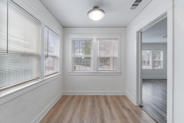 spare room featuring a textured ceiling and light wood-type flooring