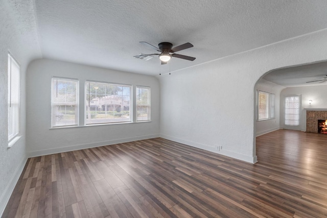 unfurnished room with a fireplace, a textured ceiling, and dark hardwood / wood-style flooring