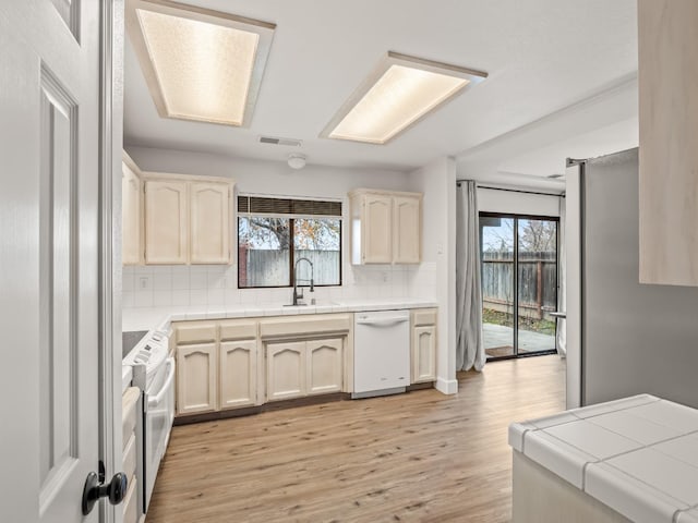 kitchen featuring tile countertops, white appliances, sink, light hardwood / wood-style flooring, and tasteful backsplash