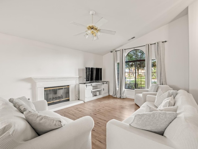 living room with ceiling fan, lofted ceiling, and light hardwood / wood-style flooring