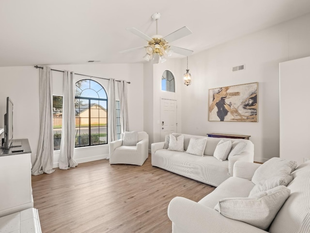 living room with light hardwood / wood-style floors, ceiling fan, and lofted ceiling