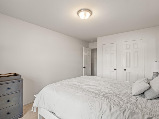 bedroom featuring light carpet and multiple closets