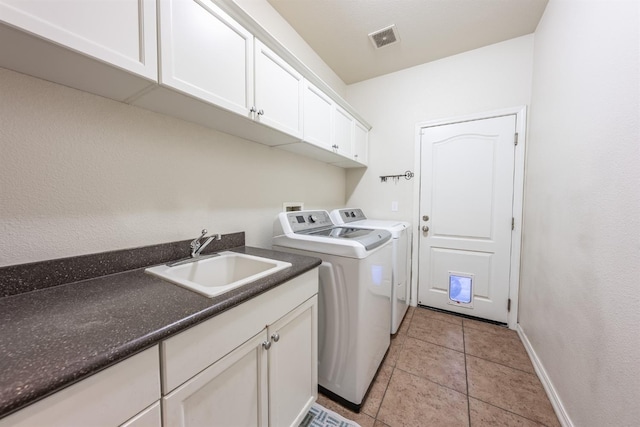 clothes washing area with cabinets, light tile patterned floors, separate washer and dryer, and sink