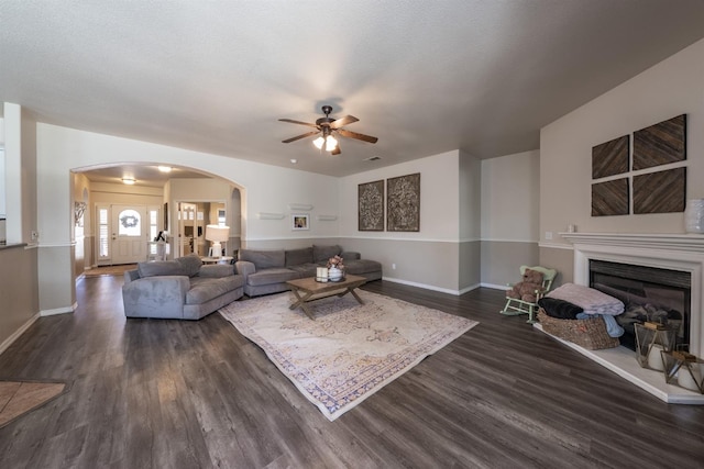 living room featuring a textured ceiling, ceiling fan, and dark wood-type flooring