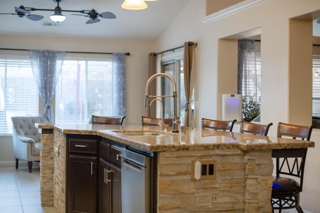 kitchen featuring lofted ceiling, sink, a center island with sink, light tile patterned floors, and a kitchen breakfast bar