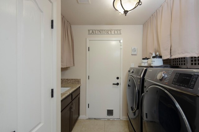 washroom with light tile patterned flooring, washing machine and clothes dryer, and cabinets