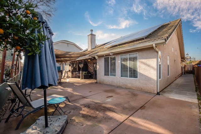 rear view of property featuring a patio area and solar panels