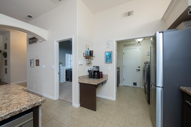 kitchen with washing machine and clothes dryer, beverage cooler, stainless steel fridge, and light tile patterned floors