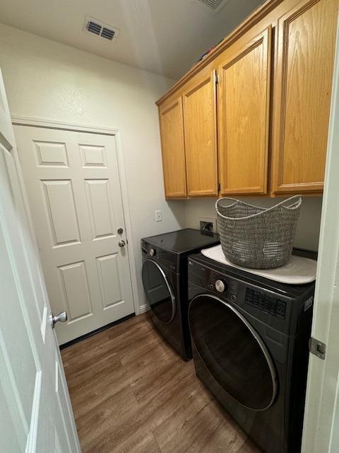 washroom with dark hardwood / wood-style flooring, washer and clothes dryer, and cabinets