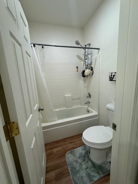 bathroom featuring shower / bath combo with shower curtain, hardwood / wood-style floors, and toilet