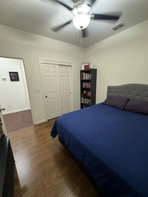 bedroom with a closet, dark hardwood / wood-style floors, and ceiling fan