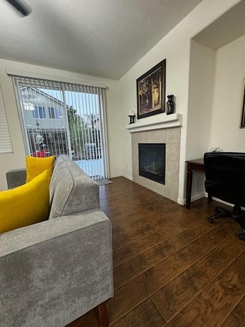 living room featuring a tile fireplace, dark wood-type flooring, and a textured ceiling