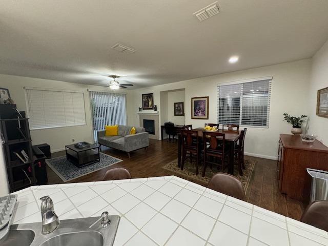 interior space with dark hardwood / wood-style flooring, tile countertops, and ceiling fan