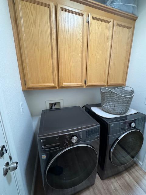 laundry area featuring washer and dryer, hardwood / wood-style floors, and cabinets