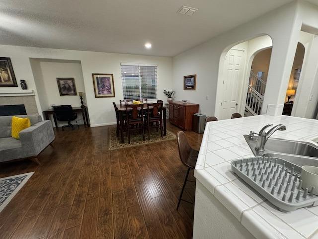 dining space featuring dark wood-type flooring and a tiled fireplace