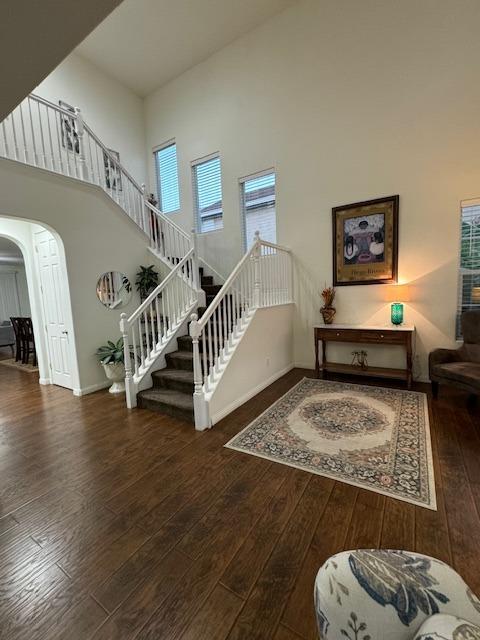 stairs featuring wood-type flooring and a high ceiling