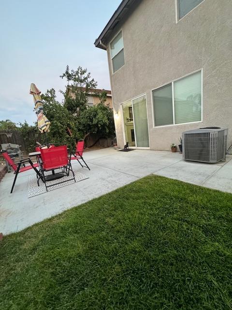 rear view of property with central air condition unit, a yard, and a patio