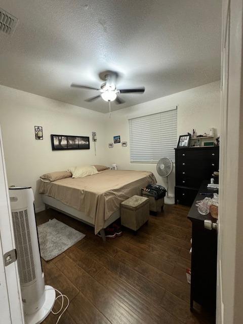 bedroom featuring ceiling fan, dark hardwood / wood-style flooring, and a textured ceiling