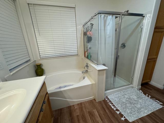 bathroom featuring plus walk in shower, hardwood / wood-style floors, and vanity