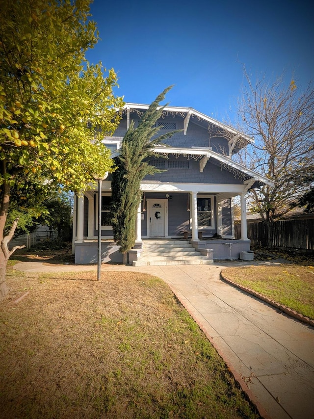 view of front of home with covered porch and a front lawn