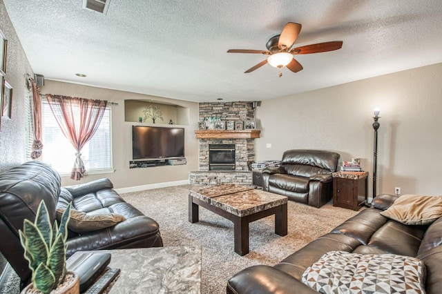 living room with a textured ceiling, ceiling fan, a stone fireplace, and light carpet