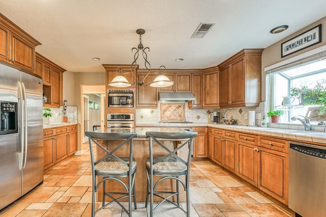 kitchen featuring decorative backsplash, stainless steel appliances, decorative light fixtures, a kitchen island, and a breakfast bar area