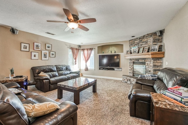 living room featuring a stone fireplace, ceiling fan, light colored carpet, and a textured ceiling