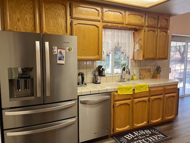 kitchen featuring backsplash, dark wood-type flooring, sink, appliances with stainless steel finishes, and tile counters